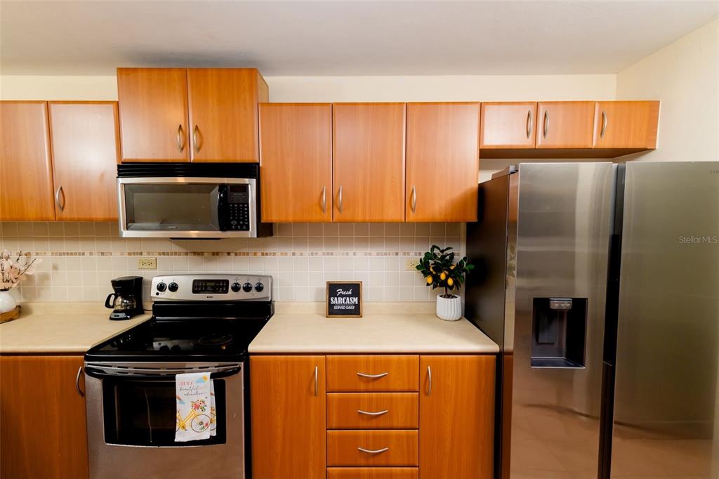 A kitchen features wood cabinets, stainless steel appliances, and a tiled backsplash — Villas del Mar MEDIANA ALTA UNIT 1, LOIZA, PR