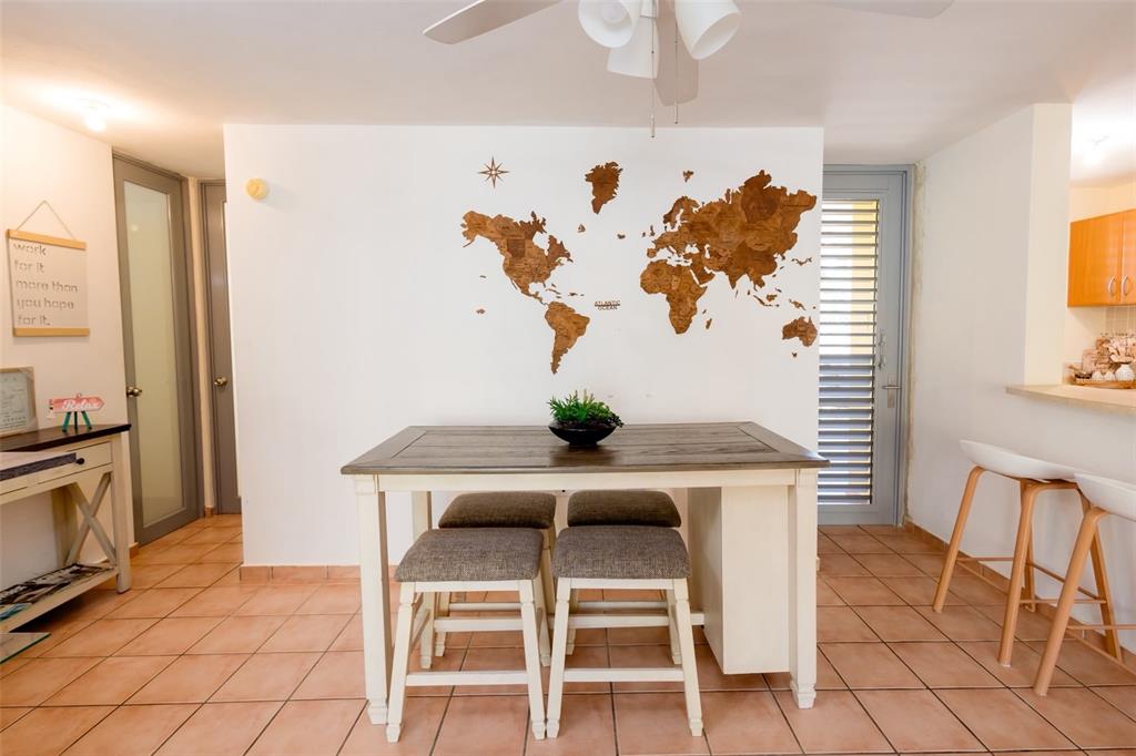 A dining area features a wooden table with four stools and a world map wall decoration — Villas del Mar MEDIANA ALTA UNIT 1, LOIZA, PR