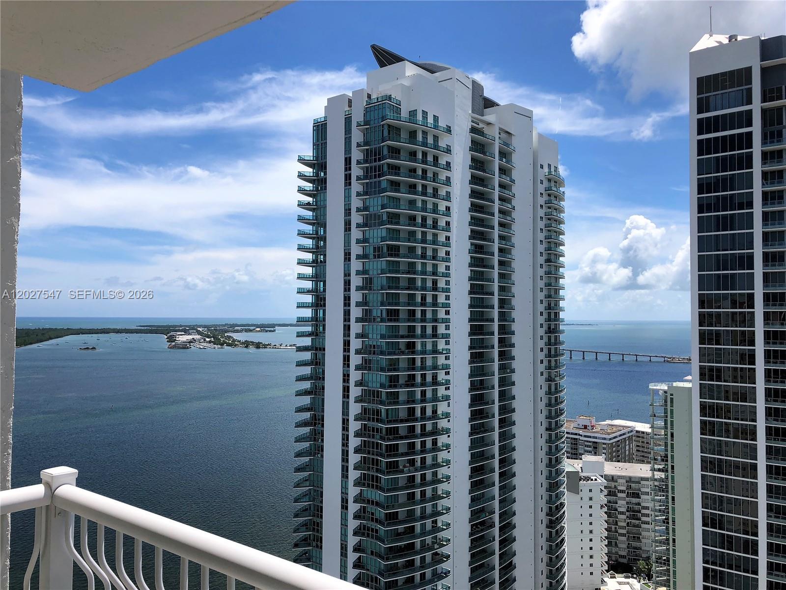 A high-rise balcony view overlooks a large bay with a bridge and neighboring skyscrapers — 1200 Brickell Bay Dr # 3903, Miami FL 33131, MIAMI, FL