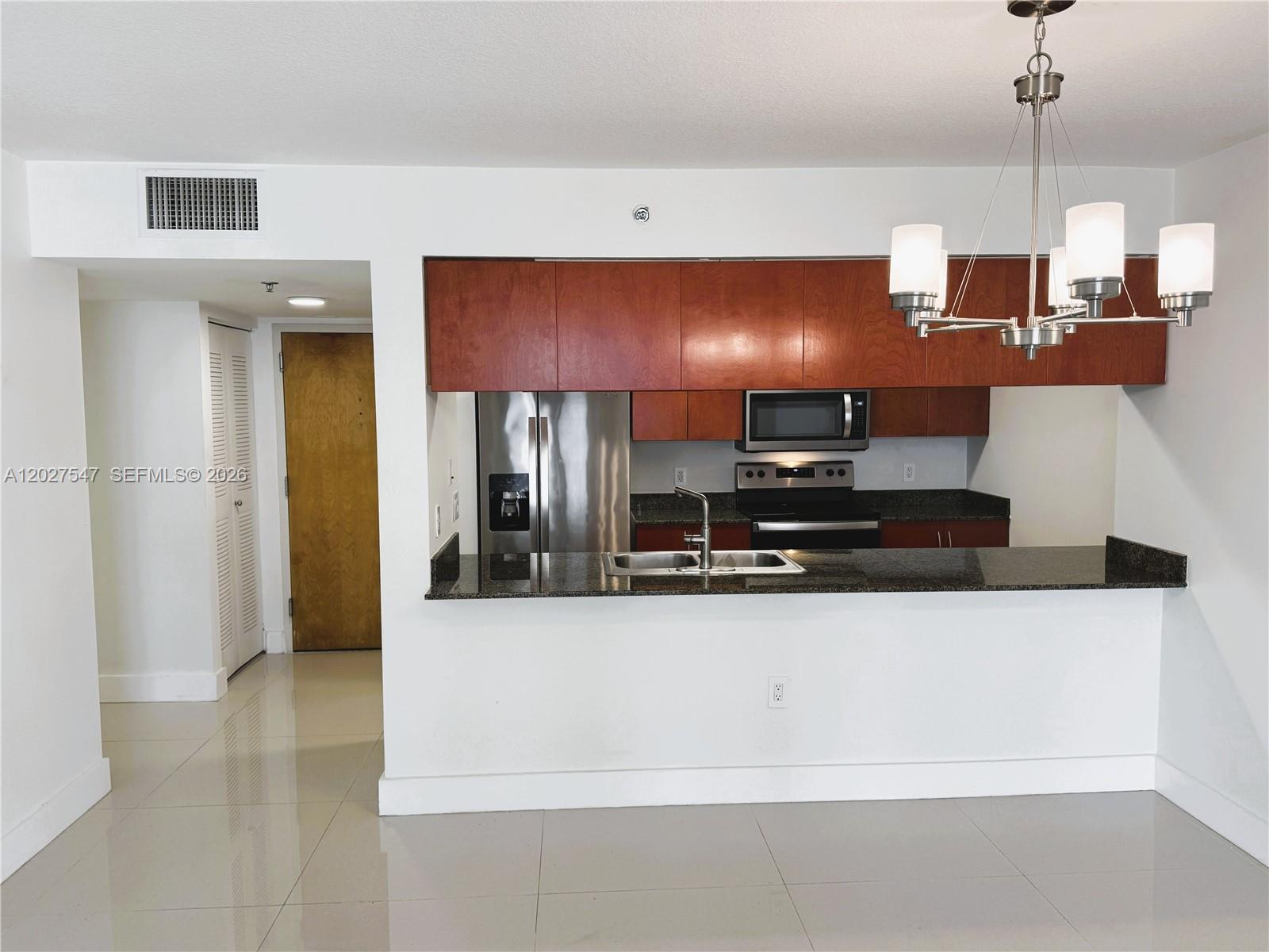 A kitchen features dark wood cabinets, stainless steel appliances, and a granite breakfast bar — 1200 Brickell Bay Dr # 3903, Miami FL 33131, MIAMI, FL