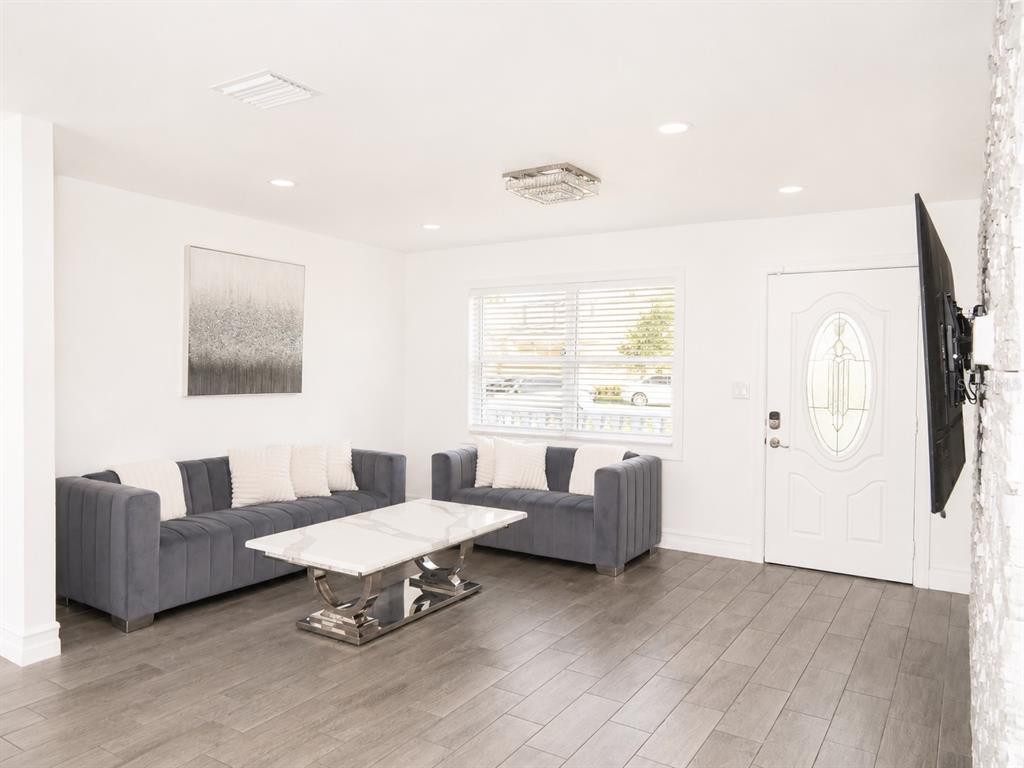 A living room features two grey velvet sofas, a marble coffee table, and tile flooring — 4741 76TH AVENUE N, PINELLAS PARK, FL