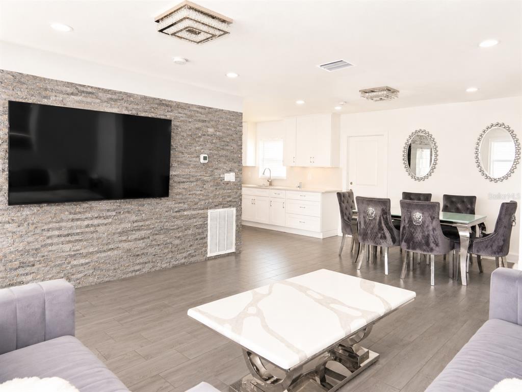A living and dining area features a stone accent wall, gray tile floors, and furniture — 4741 76TH AVENUE N, PINELLAS PARK, FL