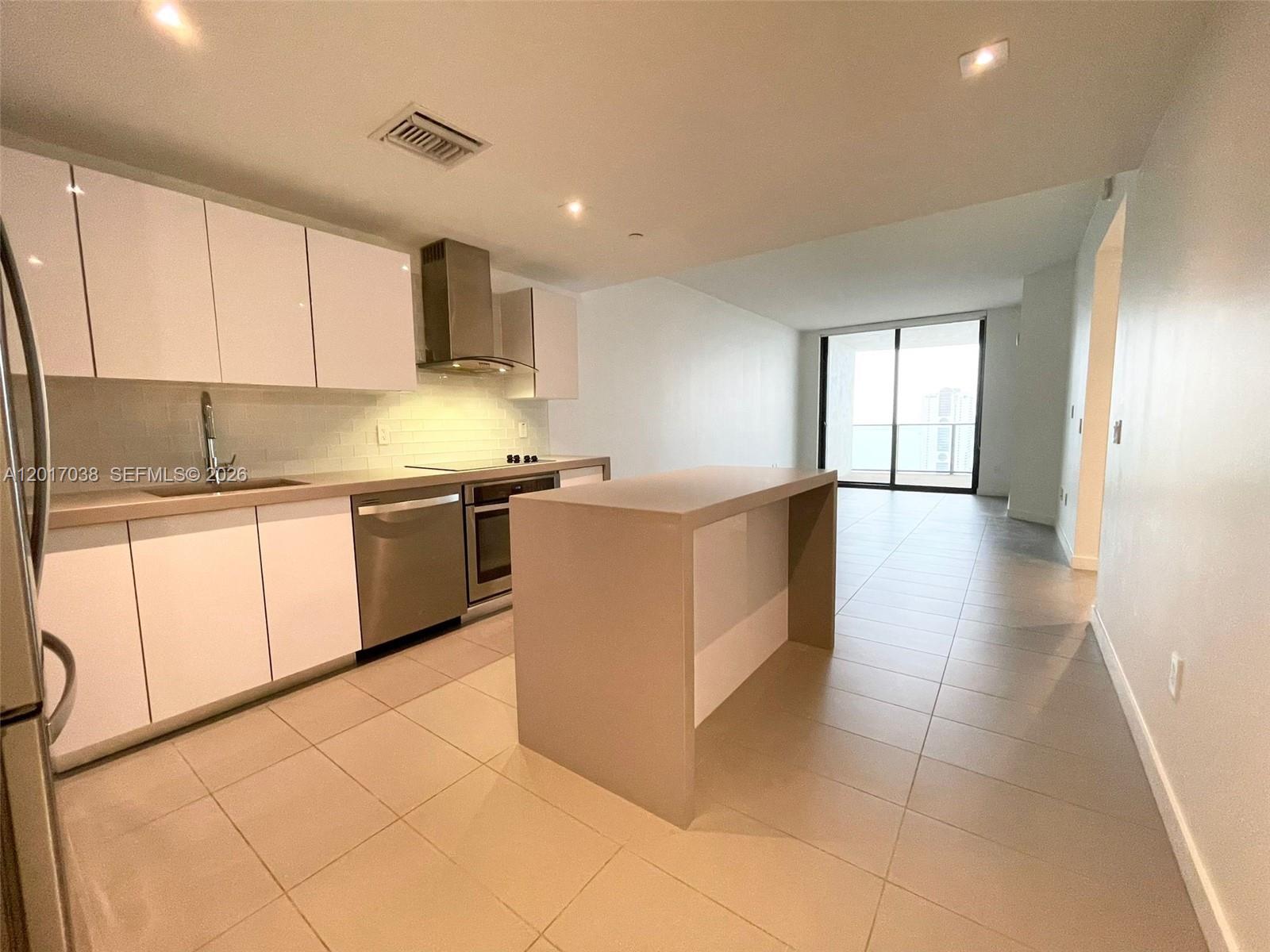 A modern kitchen features white cabinets, stainless steel appliances, and a central island — 1600 NE 1st Ave # 2405, Miami FL 33132, MIAMI, FL