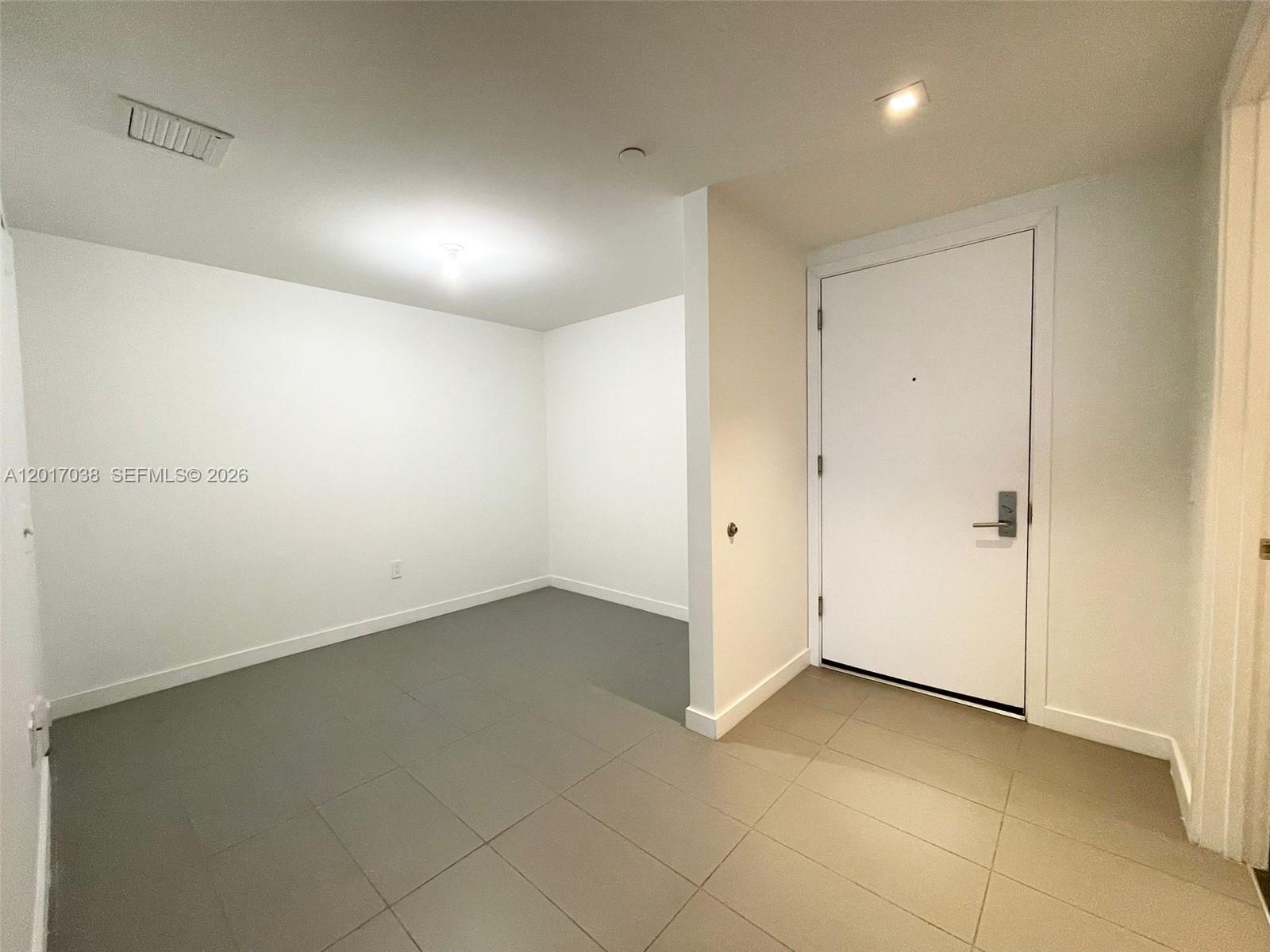 This entryway features gray tile flooring, white walls, and a white front door — 1600 NE 1st Ave # 2405, Miami FL 33132, MIAMI, FL