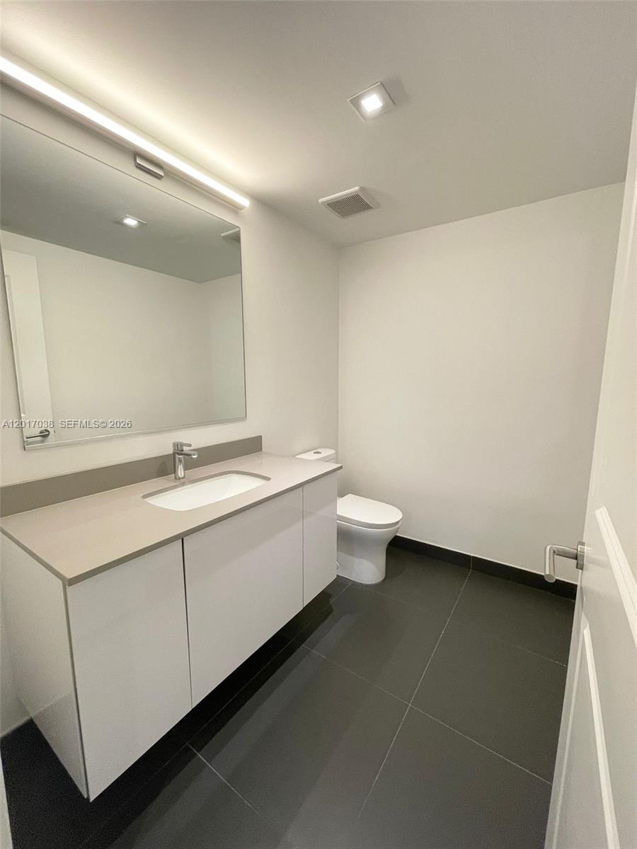 A modern bathroom features a white vanity, a large mirror, and dark gray floor tiles — 1600 NE 1st Ave # 2405, Miami FL 33132, MIAMI, FL