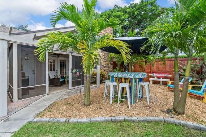 A patio with a table, stools, and umbrella sits next to a screened-in porch — 1960 Derby Trail, Wellington FL 33414, WELLINGTON, FL