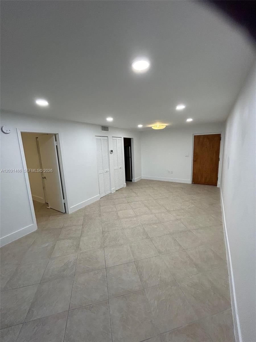 An empty room features white walls, recessed lighting, and light-colored tile flooring — 2920 SW 28th Ter # 202, Miami FL 33133, MIAMI, FL