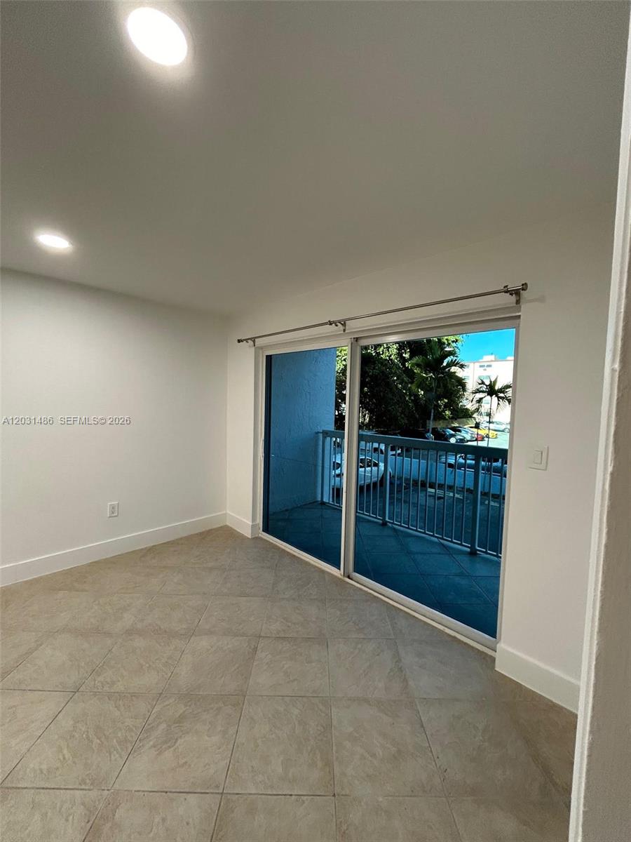 A room with tile flooring and sliding glass doors leading to a balcony — 2920 SW 28th Ter # 202, Miami FL 33133, MIAMI, FL