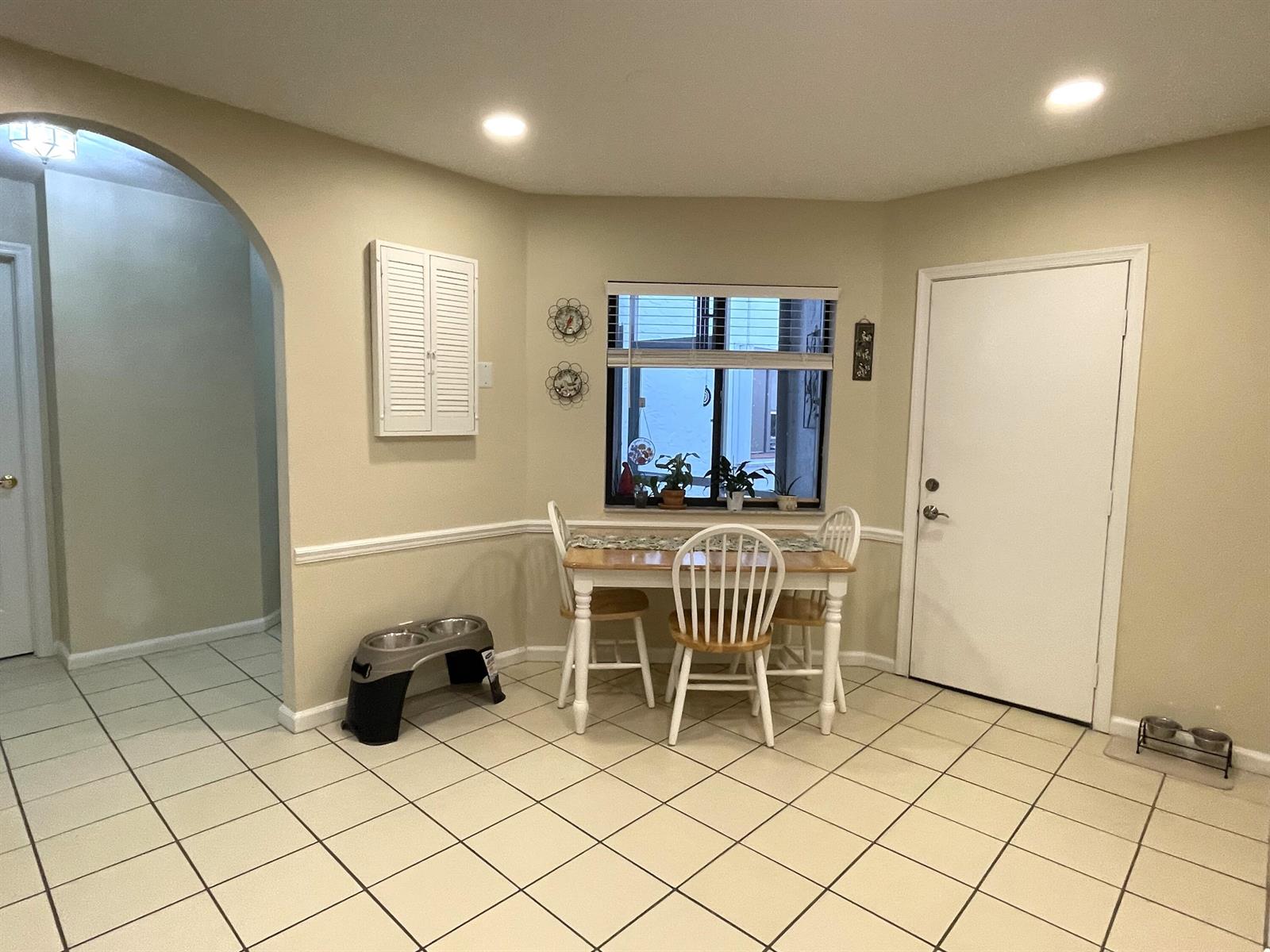 A dining nook features a small wooden table, white chairs, tiled floors, and a window — 124 Sandy Lane, Royal Palm Beach FL 33411, ROYAL PALM BEACH, FL