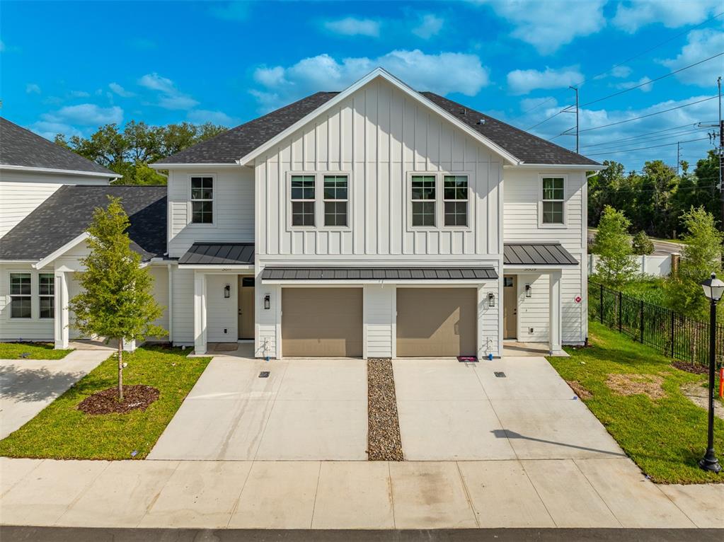 A two-story duplex with white vertical siding, dark shingled roofs, and two attached garages — 3812 FERN HOLLOW PLACE, TAMPA, FL