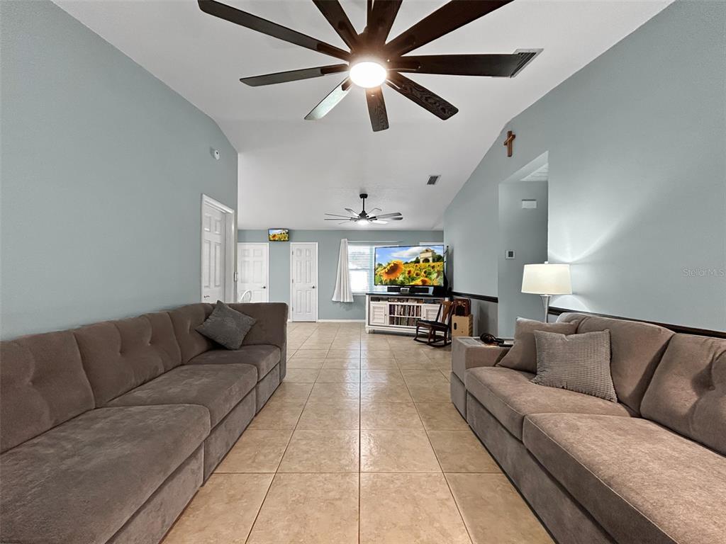 A living room features two large gray sofas, tile flooring, and a vaulted ceiling — 136 PAUL REVERE ROAD, BARTOW, FL