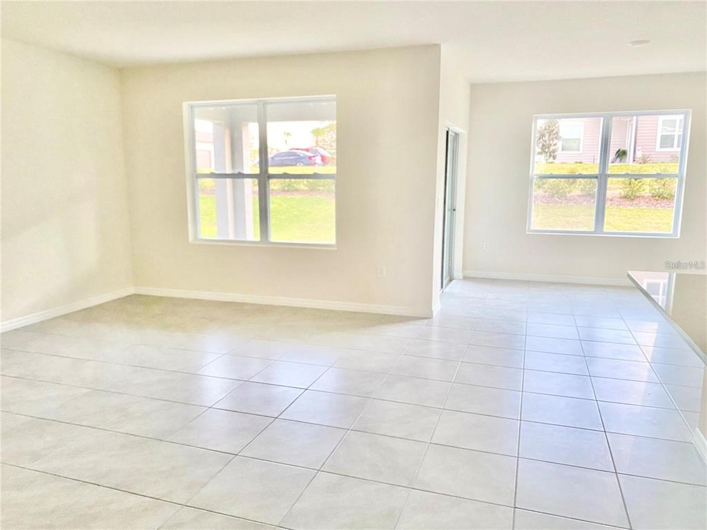 An open-concept living area features light-colored tile flooring, neutral walls, and two large windows — 2637 ROWAN STREET, TAVARES, FL