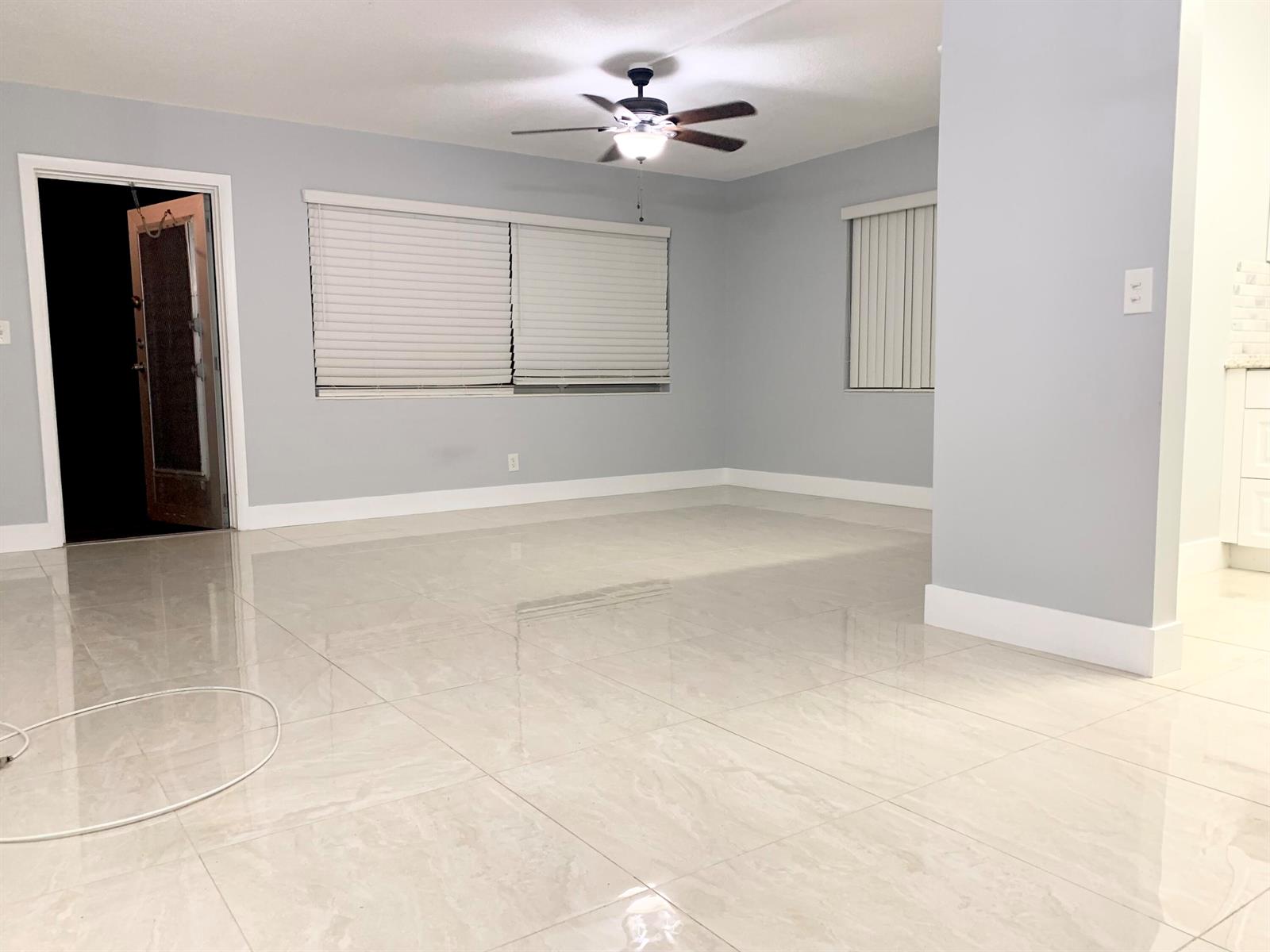 An empty room with light gray walls, large glossy floor tiles, and a ceiling fan — 200 Sheffield I, West Palm Beach FL 33417, WEST PALM BEACH, FL