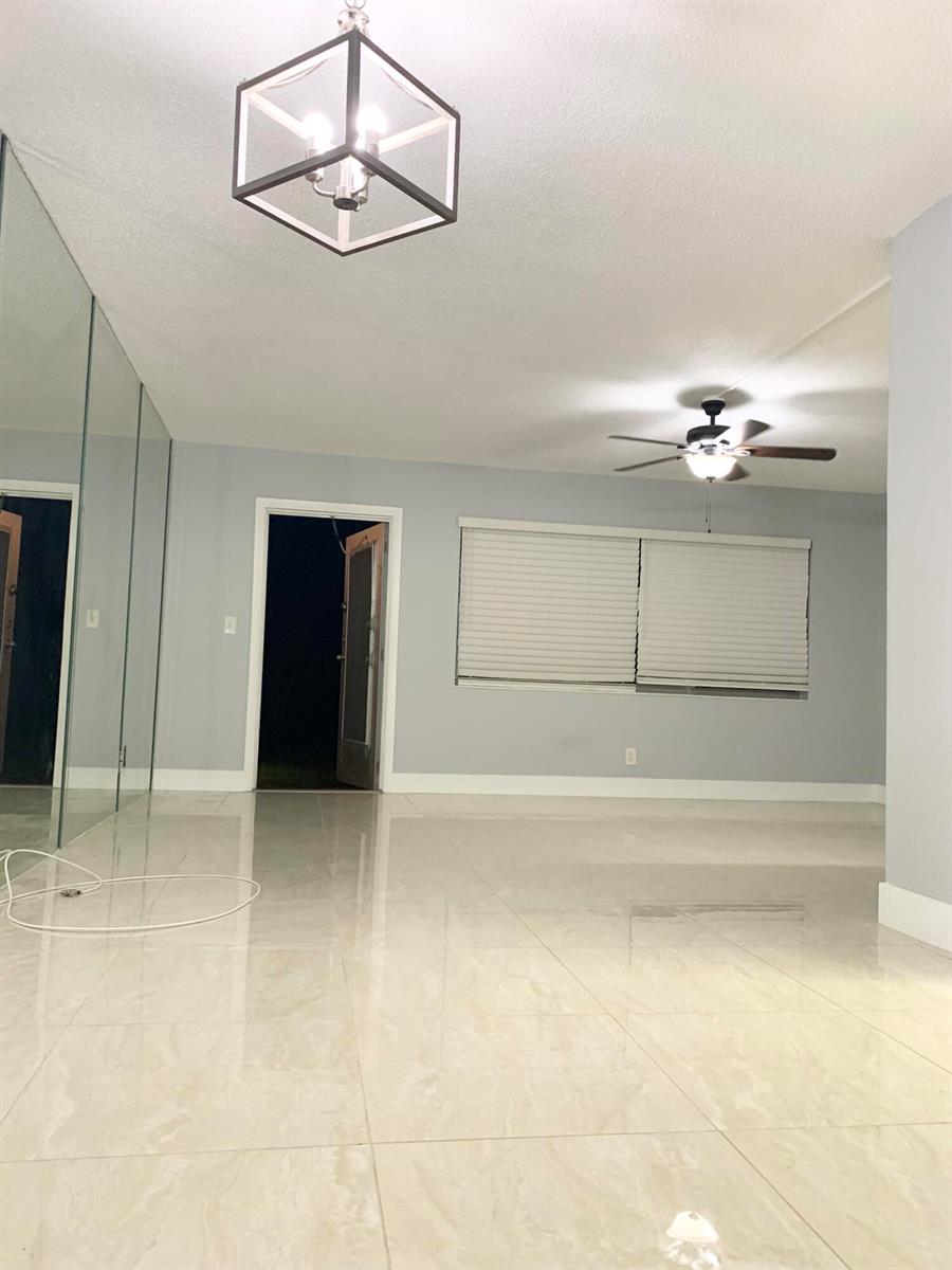 A room with light gray walls, large beige floor tiles, a ceiling fan, and mirrored walls — 200 Sheffield I, West Palm Beach FL 33417, WEST PALM BEACH, FL