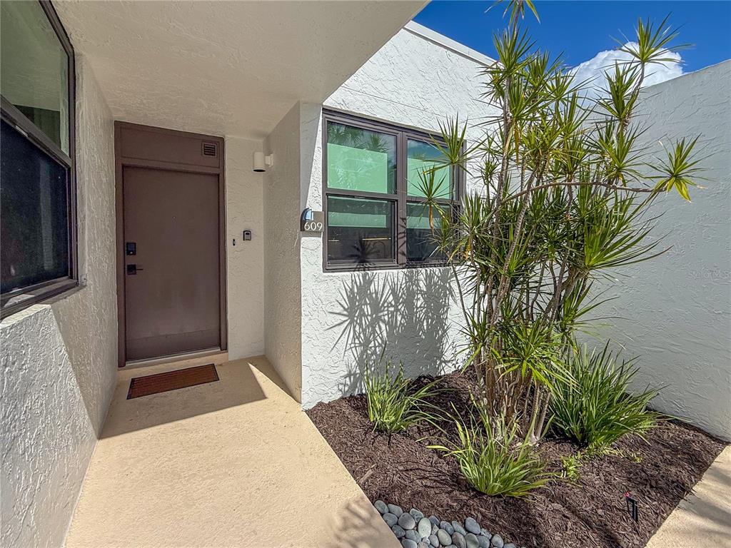 The exterior entrance features a brown door, a window, and a small garden area — 609 BAYPORT WAY UNIT 609, LONGBOAT KEY, FL