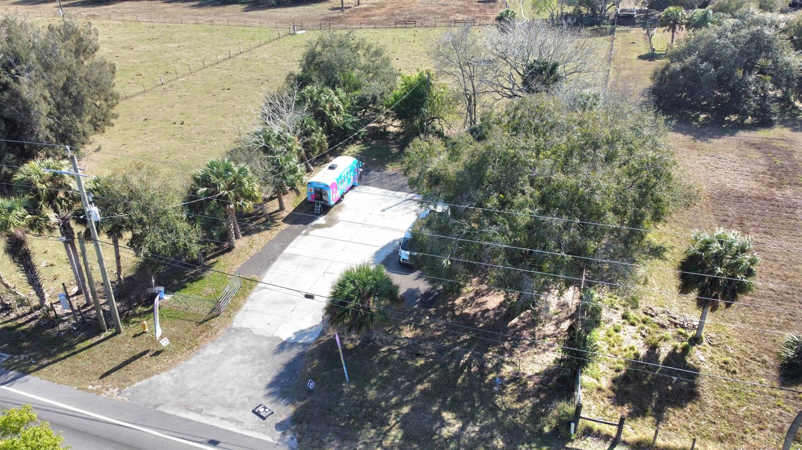 An aerial view shows a concrete driveway with a food truck parked near trees — 2594 Hwy 70 W, Okeechobee FL 34974, OKEECHOBEE, FL
