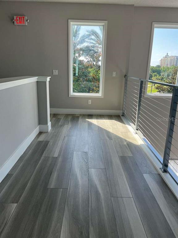 A hallway with wood-look flooring, a tall window, and a metal railing overlooking the outdoors — 7760 SANDY RIDGE DRIVE UNIT 222, REUNION, FL