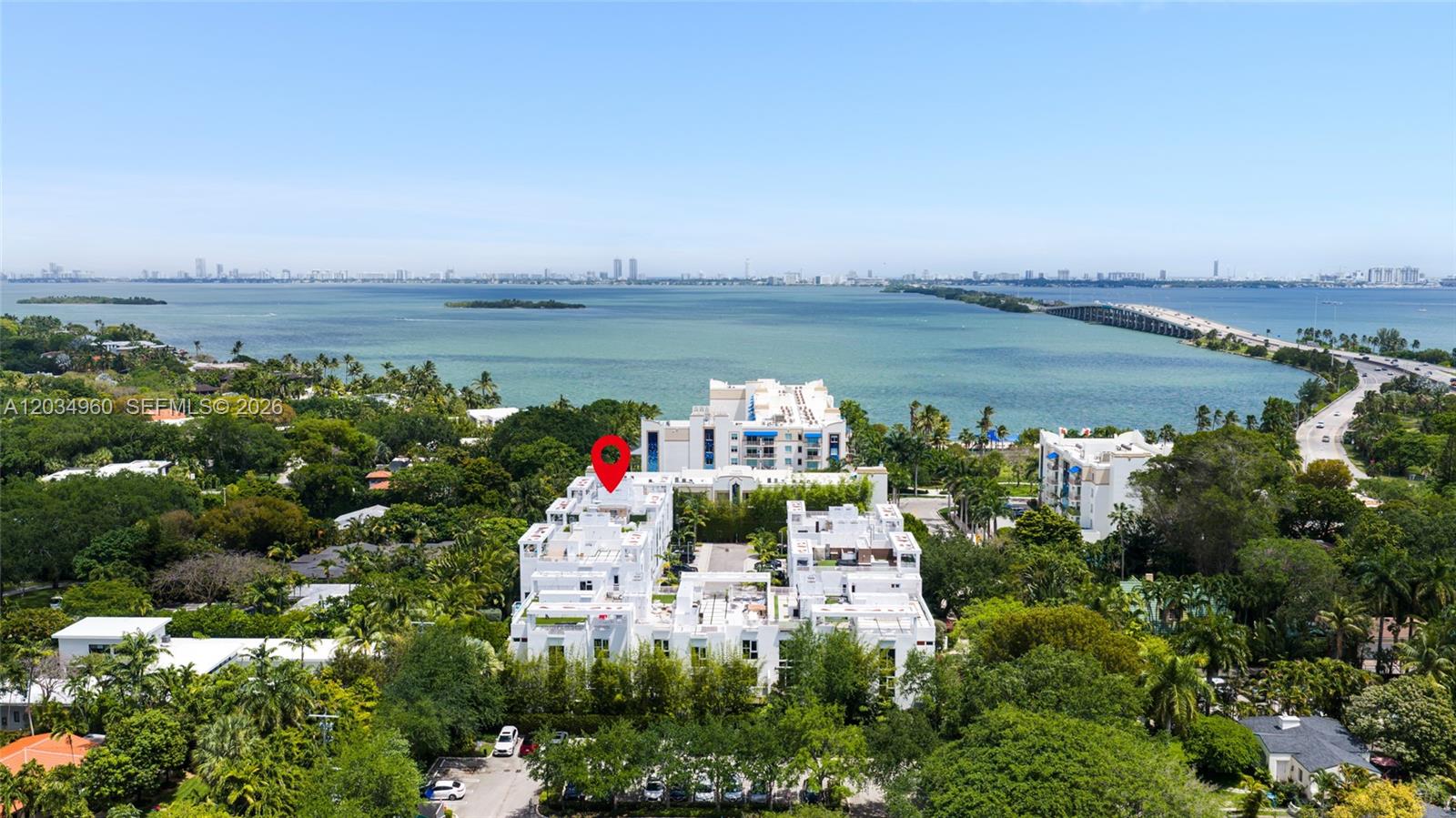An aerial view shows a white multi-story residential complex surrounded by trees near water — 455 NE 39th # 311, Miami FL 33137, MIAMI, FL