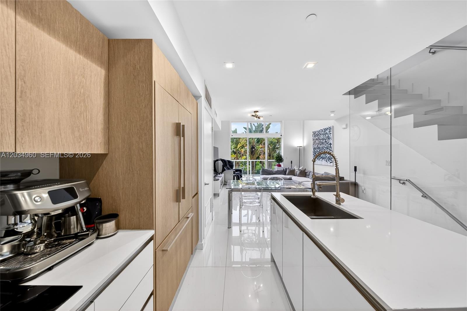 A modern kitchen with light wood cabinetry and a white island overlooks a living area — 455 NE 39th # 311, Miami FL 33137, MIAMI, FL