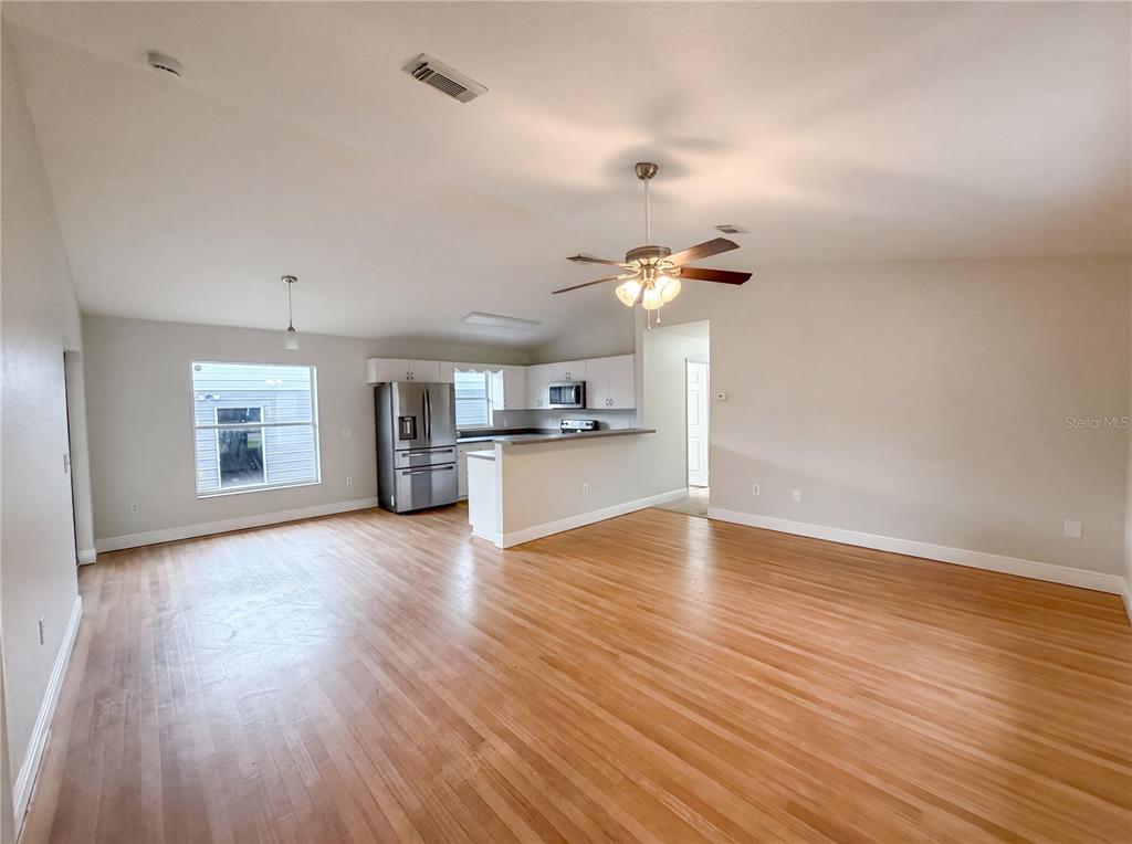 An open-concept living and dining area features hardwood floors, a ceiling fan, and a kitchen — 9295 SE 163RD STREET, SUMMERFIELD, FL