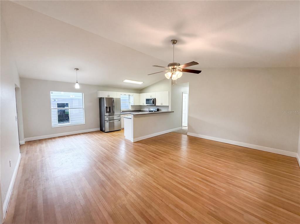 An open-concept living and dining area features hardwood floors, a ceiling fan, and a kitchen — 9295 SE 163RD STREET, SUMMERFIELD, FL