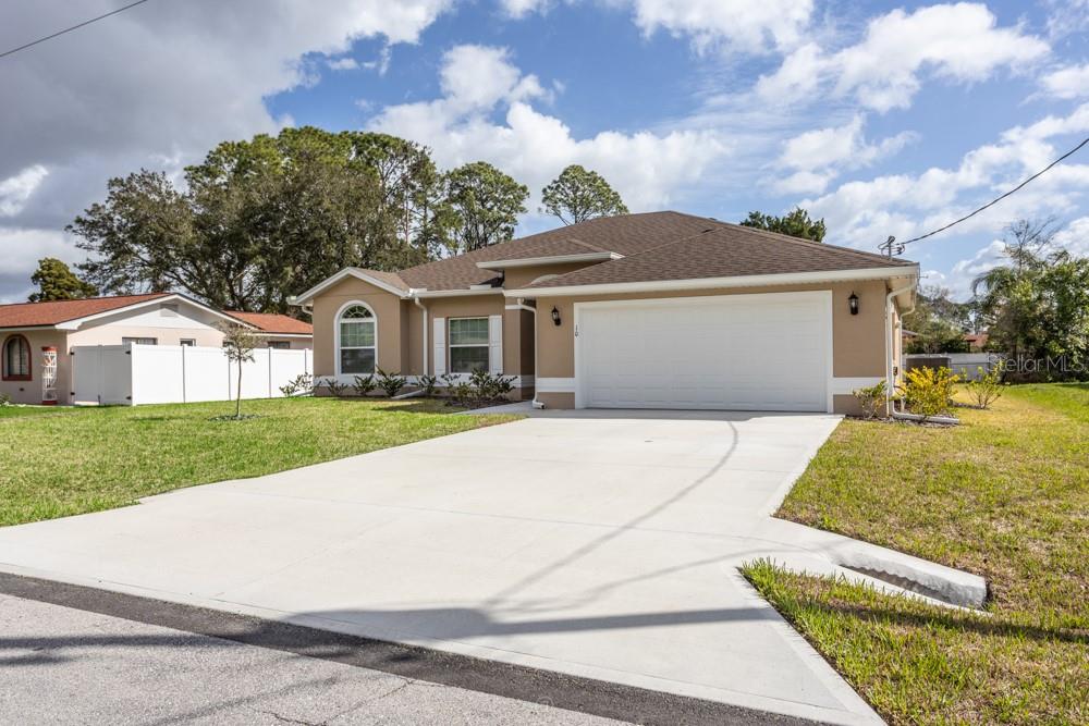 A single-story house with a tan exterior, a two-car garage, and a concrete driveway — 10 FISCHER LANE, PALM COAST, FL