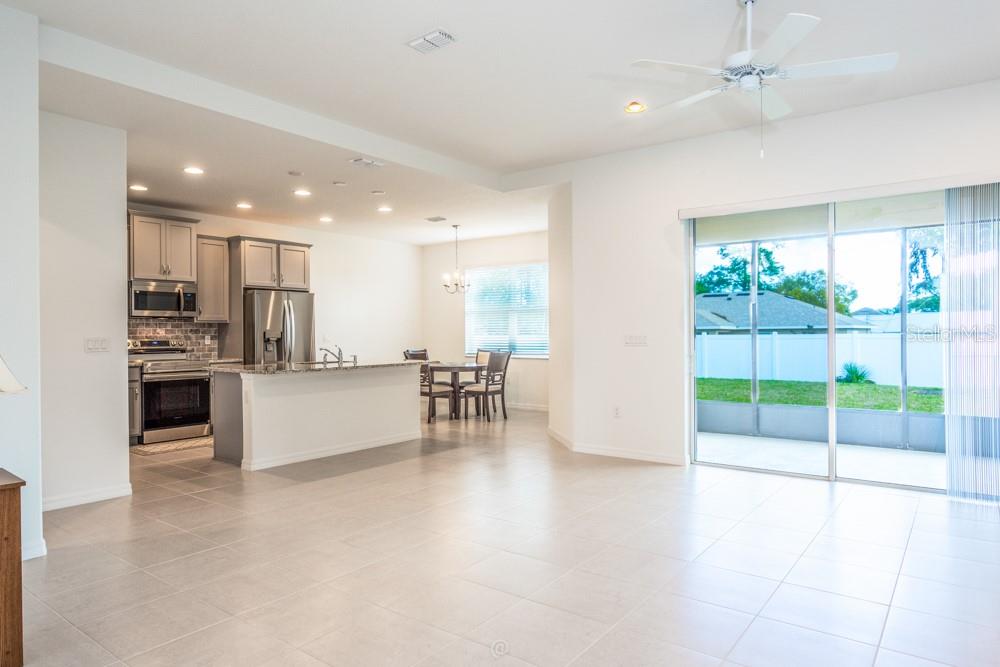 An open-concept kitchen and dining area with gray cabinets, stainless appliances, and tile flooring — 10 FISCHER LANE, PALM COAST, FL