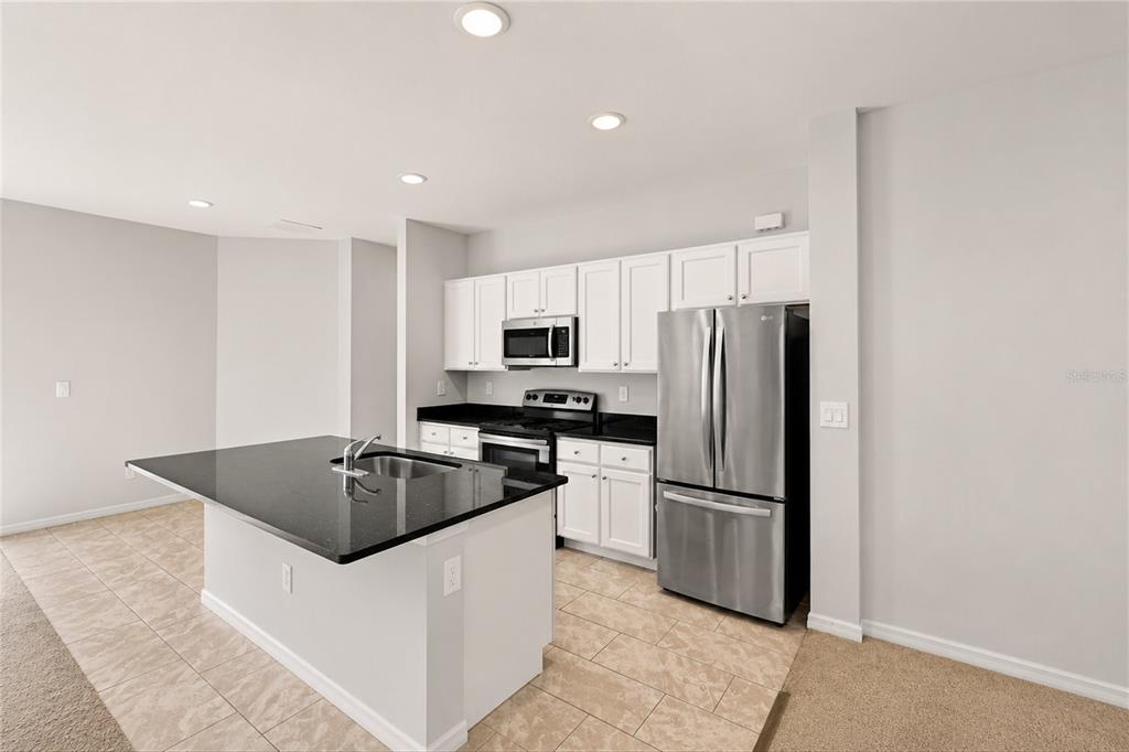 A kitchen features white cabinets, black countertops, stainless steel appliances, and a central island — 218 CAYUGA STREET, PORT CHARLOTTE, FL