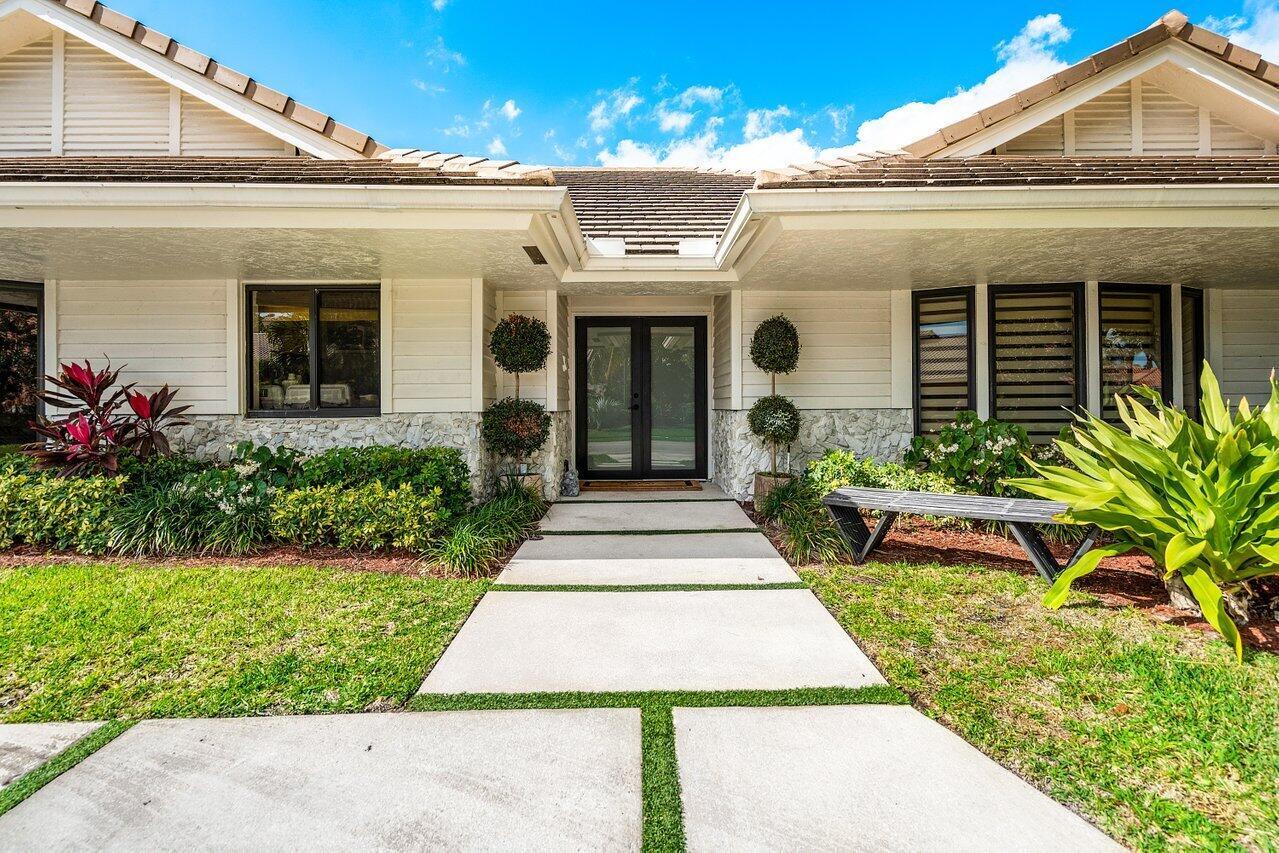 A concrete walkway leads to the front entrance of a single-story house with stone siding — 3765 Kings Way, Boca Raton FL 33434, BOCA RATON, FL