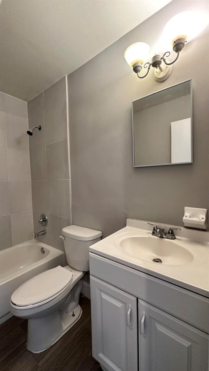 A bathroom featuring a white vanity, a toilet, and a bathtub with tiled walls — 105 NE 6th Avenue, Boynton Beach FL 33435, BOYNTON BEACH, FL