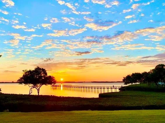 A wooden pier extends into a calm body of water during a vibrant sunset — 749 MANATEE AVENUE UNIT 749, HOLMES BEACH, FL