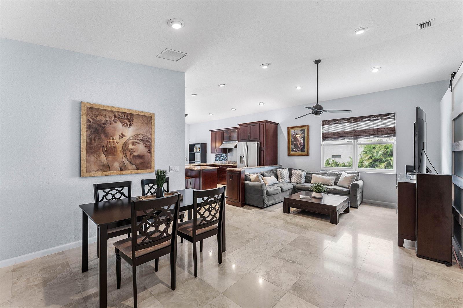An open-concept living and dining area features tile flooring, dark wood furniture, and a kitchen — 7076 Middlebury Drive, Boynton Beach FL 33436, BOYNTON BEACH, FL