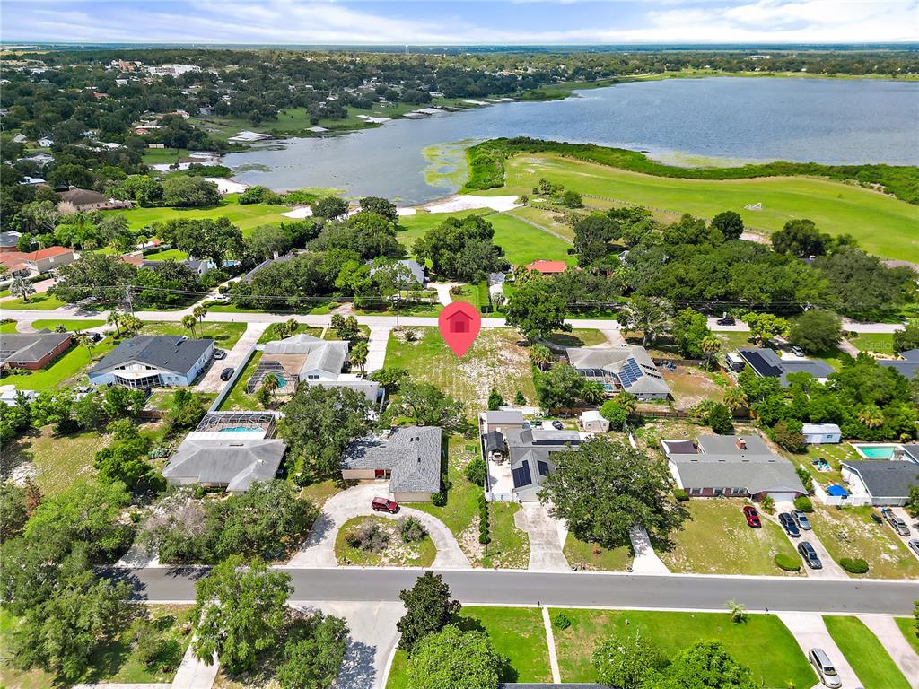 An aerial view shows a vacant residential lot situated between houses near a large lake — 0 LAKESHORE BOULEVARD N, LAKE WALES, FL