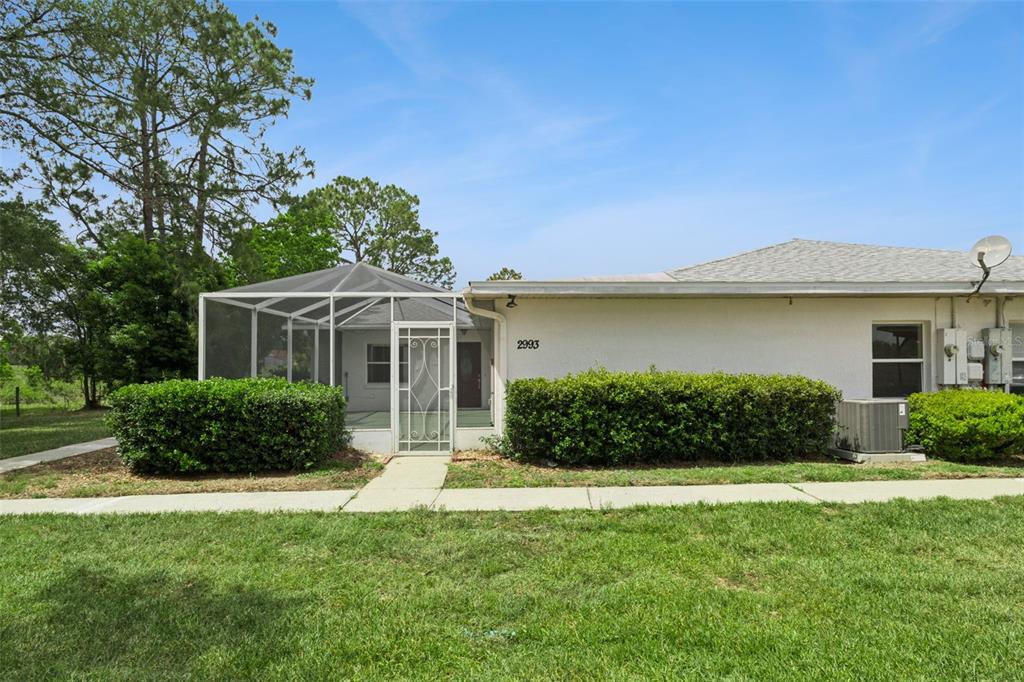 A single-story residential building features a screened-in porch and a manicured hedge in front — 2993 POPLAR AVENUE, LEESBURG, FL