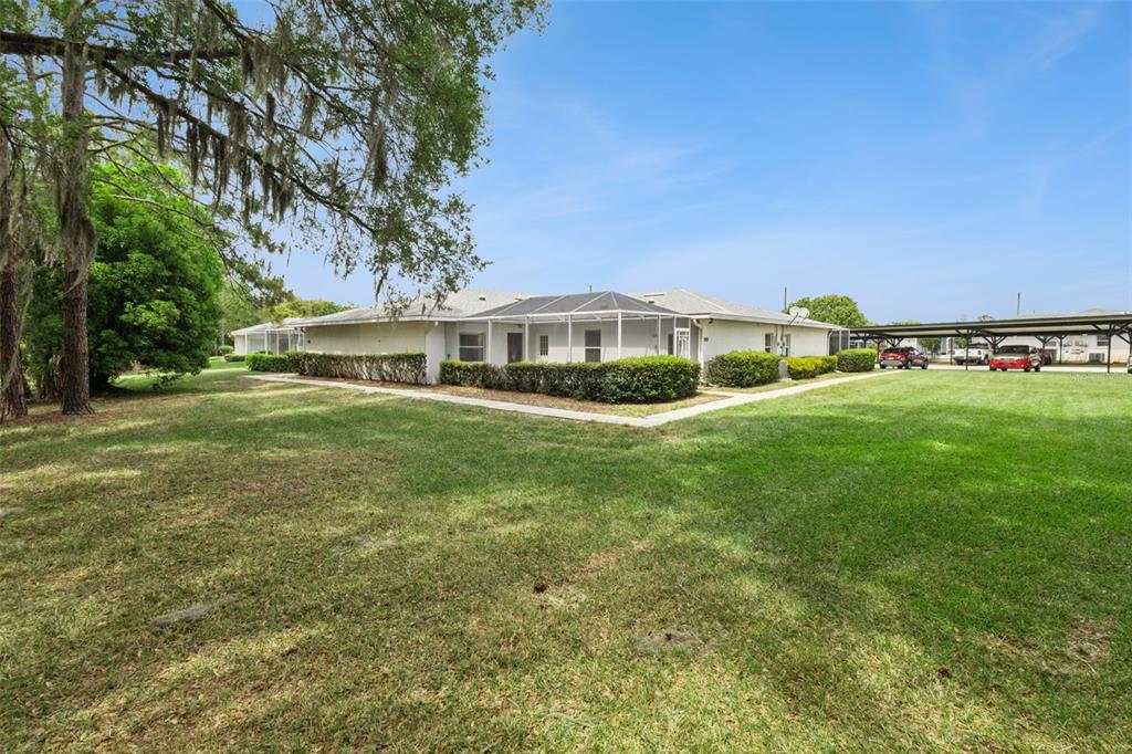 A low-rise residential building with a screened-in patio sits on a large, grassy lawn — 2993 POPLAR AVENUE, LEESBURG, FL