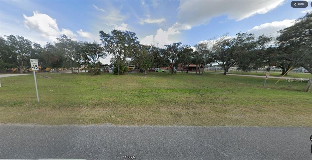 A vacant, grassy lot with scattered trees is bordered by a road and a speed limit sign — N/A, POLK CITY, FL