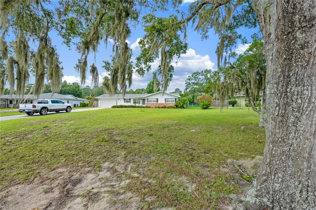 A white pickup truck is parked in the driveway of a single-story house with trees — 415 HIAWATHA AVENUE, INVERNESS, FL