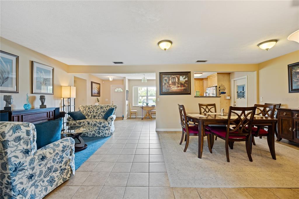 An open-concept living and dining area with tile floors, floral furniture, and a kitchen pass-through — 415 HIAWATHA AVENUE, INVERNESS, FL