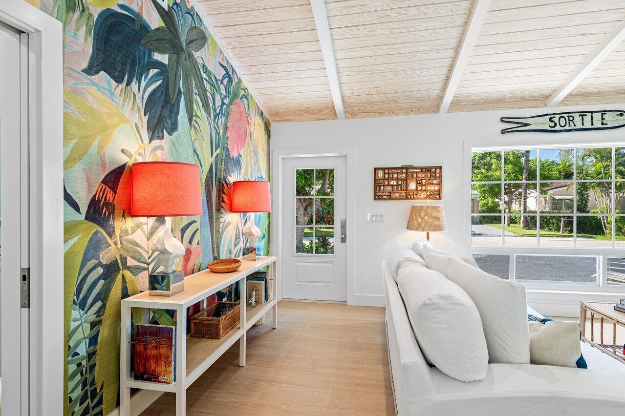 A living room features a tropical wallpaper accent wall, white sofa, and wood-paneled ceiling — 11 Hersey Drive, Ocean Ridge FL 33435, OCEAN RIDGE, FL