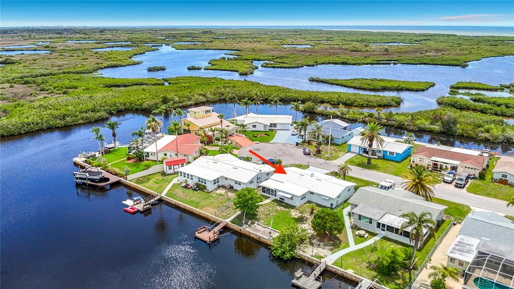 An aerial view shows a white waterfront house with a dock along a canal — 12524 5TH ISLE, HUDSON, FL