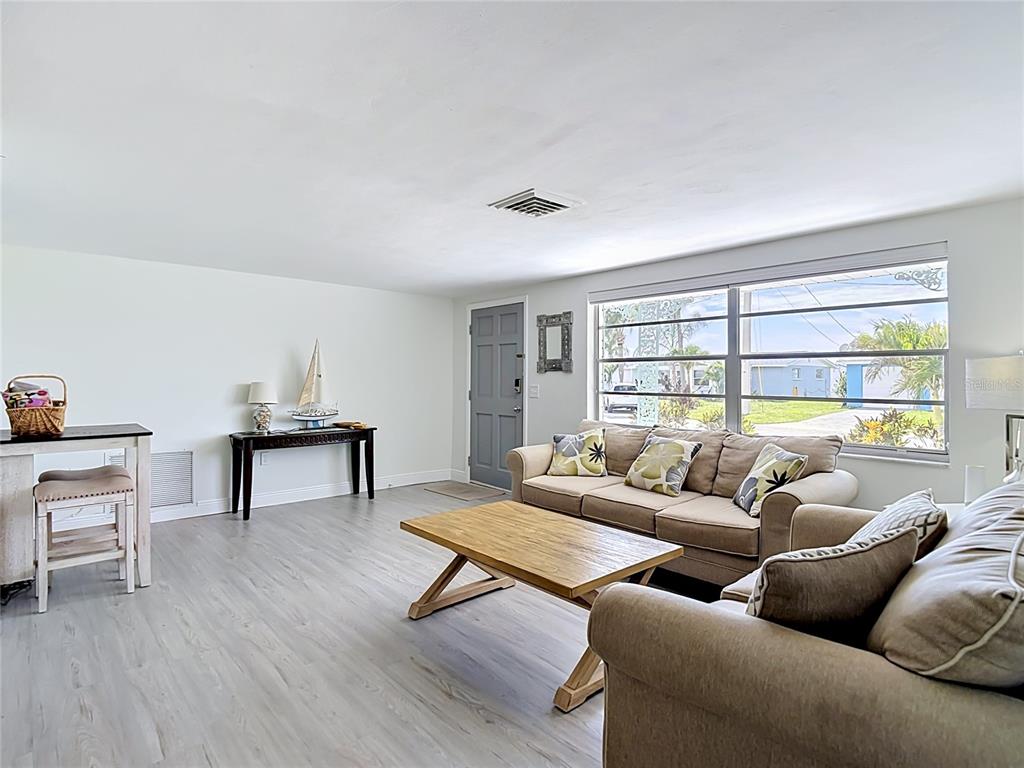 A living room features light wood-look flooring, a beige sofa, and a large window — 12524 5TH ISLE, HUDSON, FL