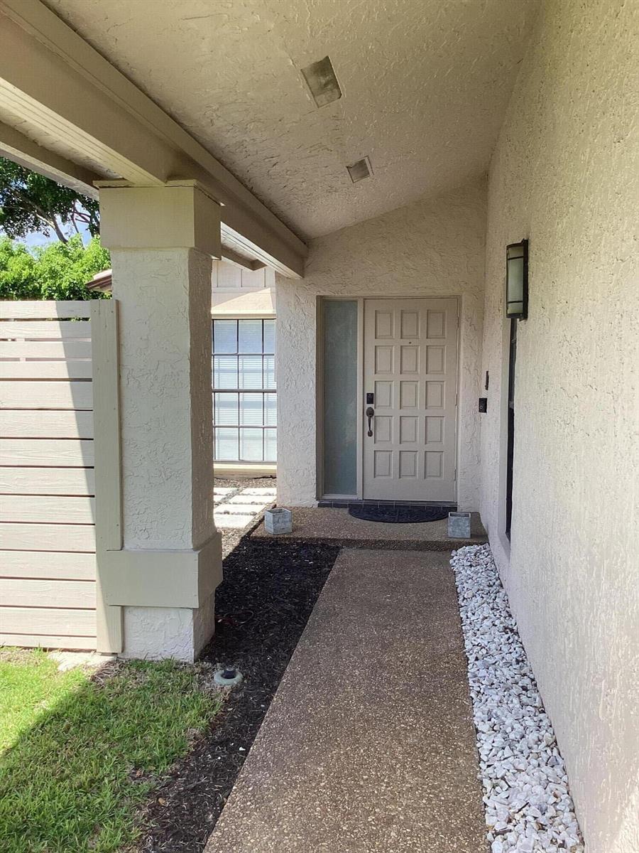 A covered concrete walkway leads to a beige front door with a side window panel — 8895 Old Pine Road, Boca Raton FL 33433, BOCA RATON, FL