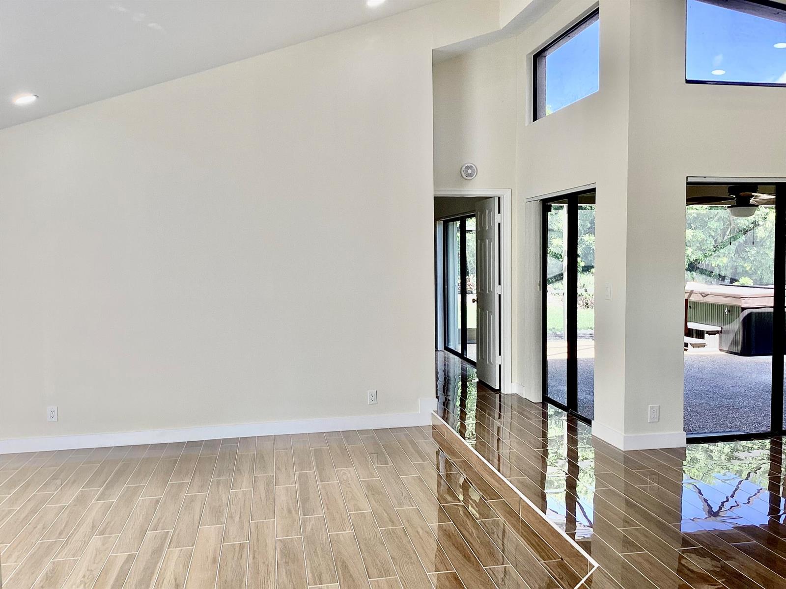 A bright room features light-colored walls, wood-look tile flooring, and sliding glass doors to a patio — 8895 Old Pine Road, Boca Raton FL 33433, BOCA RATON, FL
