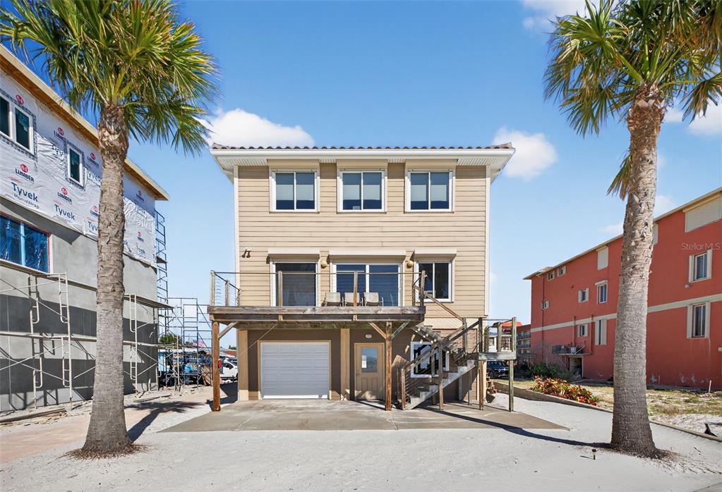 A two-story house with tan siding, a raised deck, and a ground-level garage — 17610 LEE AVENUE, REDINGTON SHORES, FL