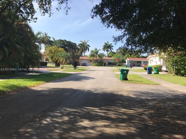 A residential street view featuring houses, palm trees, and green trash bins on the curb — 11400 NE 4 Ave # 2, Miami FL 33161, MIAMI, FL