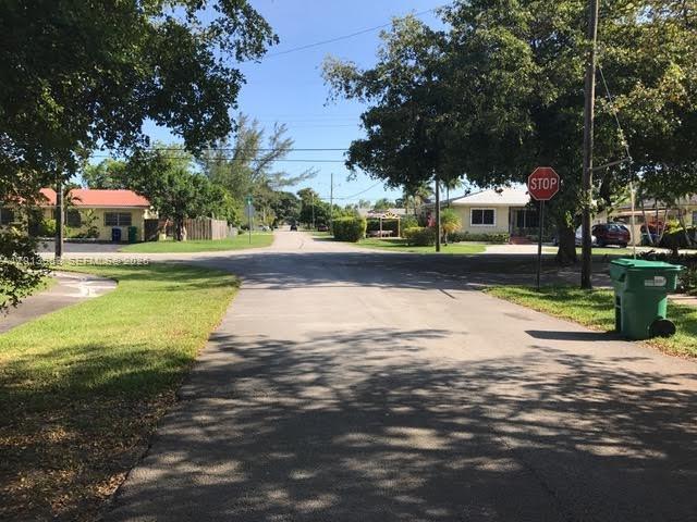 A residential street scene features a stop sign, green trash bin, and nearby houses — 11400 NE 4 Ave # 2, Miami FL 33161, MIAMI, FL