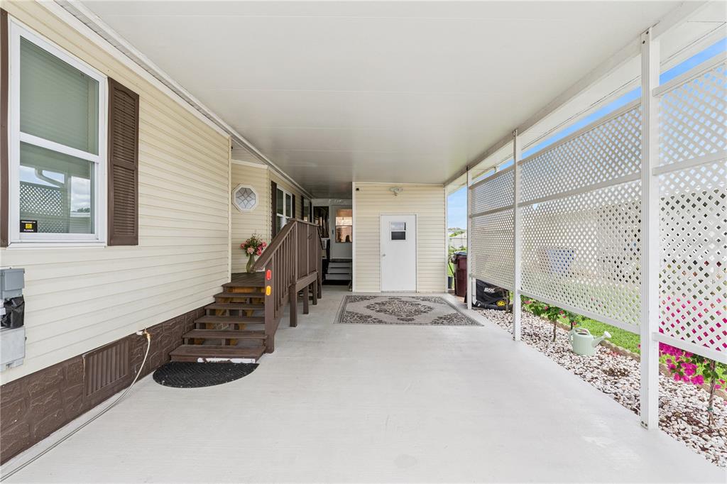 A covered carport with a set of wooden stairs leading to a side entrance — 2473 INDEPENDENCE LANE, ST CLOUD, FL