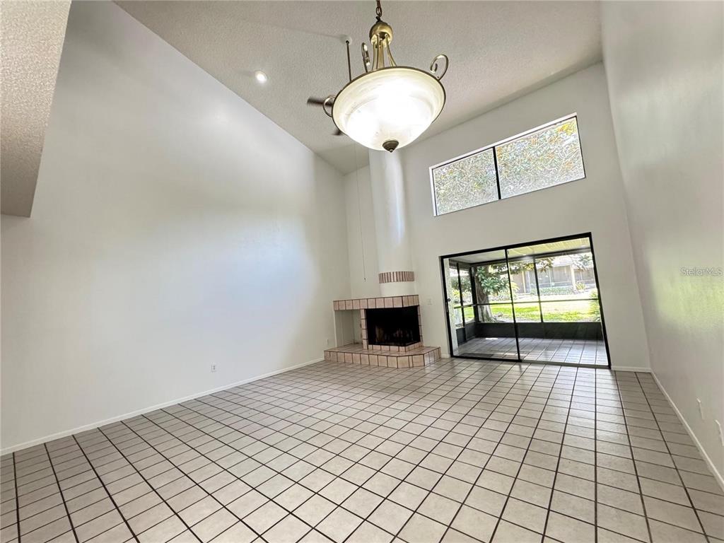 A living room with high ceilings, tile flooring, a fireplace, and a sliding glass door — 497 CLUB DRIVE, WINTER SPRINGS, FL