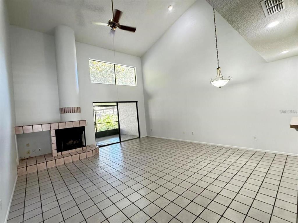 A living room features a tiled floor, a fireplace, a ceiling fan, and vaulted ceilings — 497 CLUB DRIVE, WINTER SPRINGS, FL