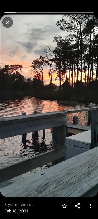 A wooden dock overlooks a calm body of water at sunset with silhouetted trees — 230 SUE AVENUE, DAVENPORT, FL